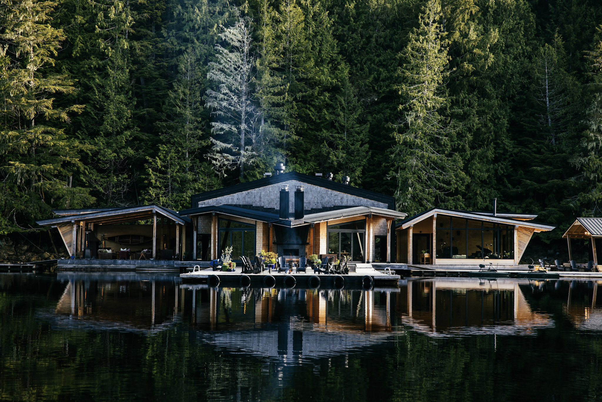 Little River restaurant and lounge lit at dusk, reflected in the still water at Nimmo Bay