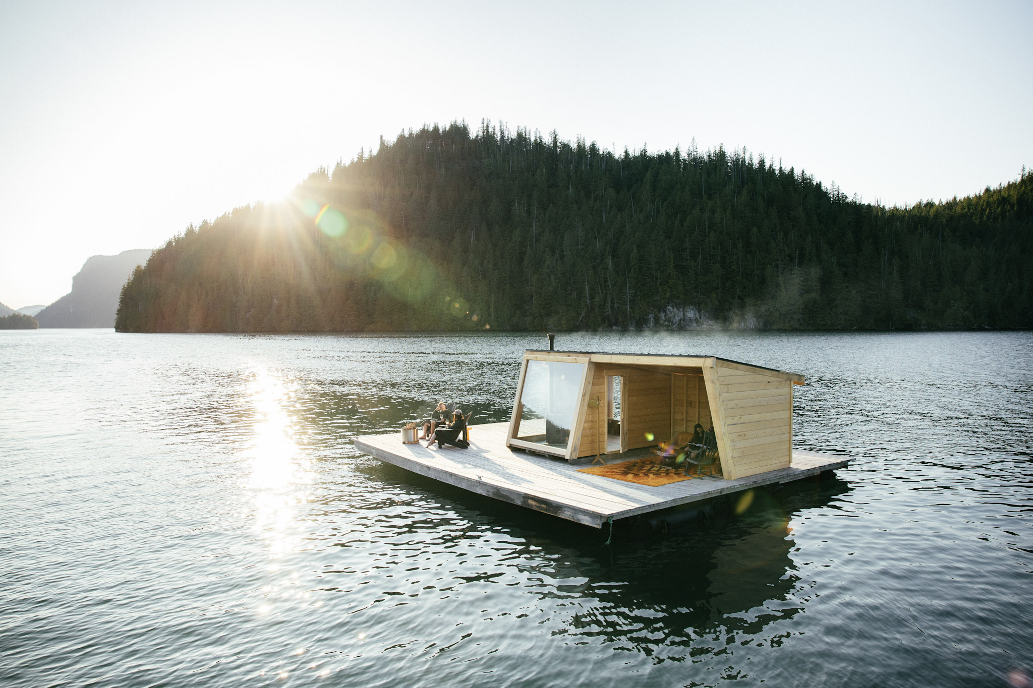 Nimmo Bay's floating sauna out on the open water, backed by a forested ridge and low sun