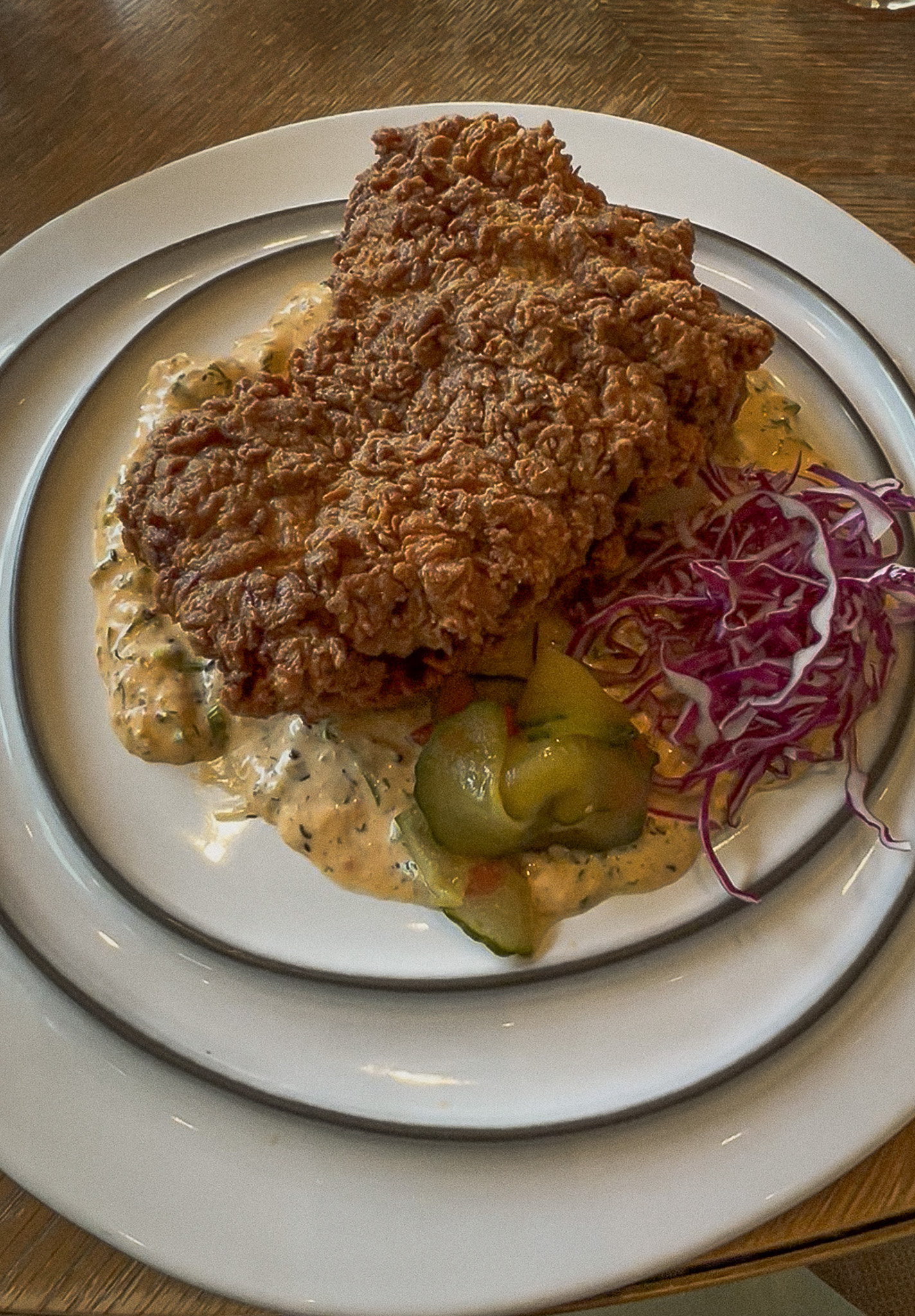Pollo frito at San Laurel Los Angeles, a crisp fried chicken cutlet with herb sauce, pickled cucumber and purple cabbage