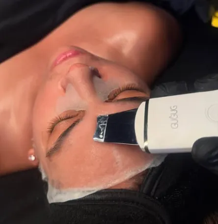 Woman receiving a facial skin treatment with a metallic handheld device on her forehead.