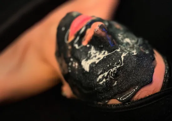 Close-up of a hand wearing a fingerless glove with black, white, and red paint splatters.