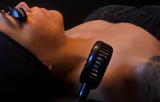 Person wearing protective goggles receiving a therapy treatment on the neck with a handheld device.
