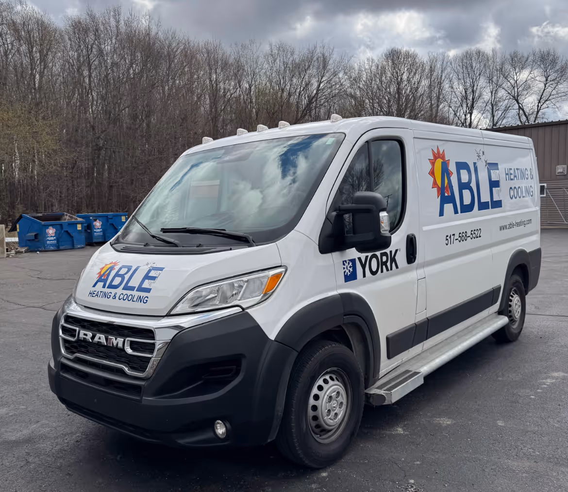 White RAM van with Able Heating & Cooling and York logos parked on pavement near bare trees.