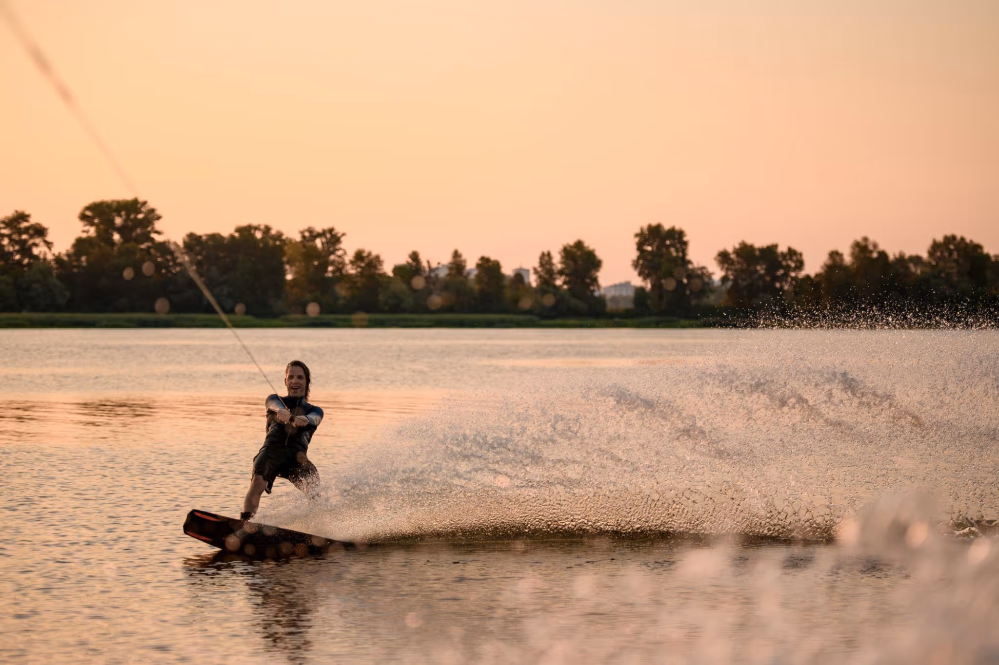 Smiling couple embracing on a boat at sunset with city skyline in the background.