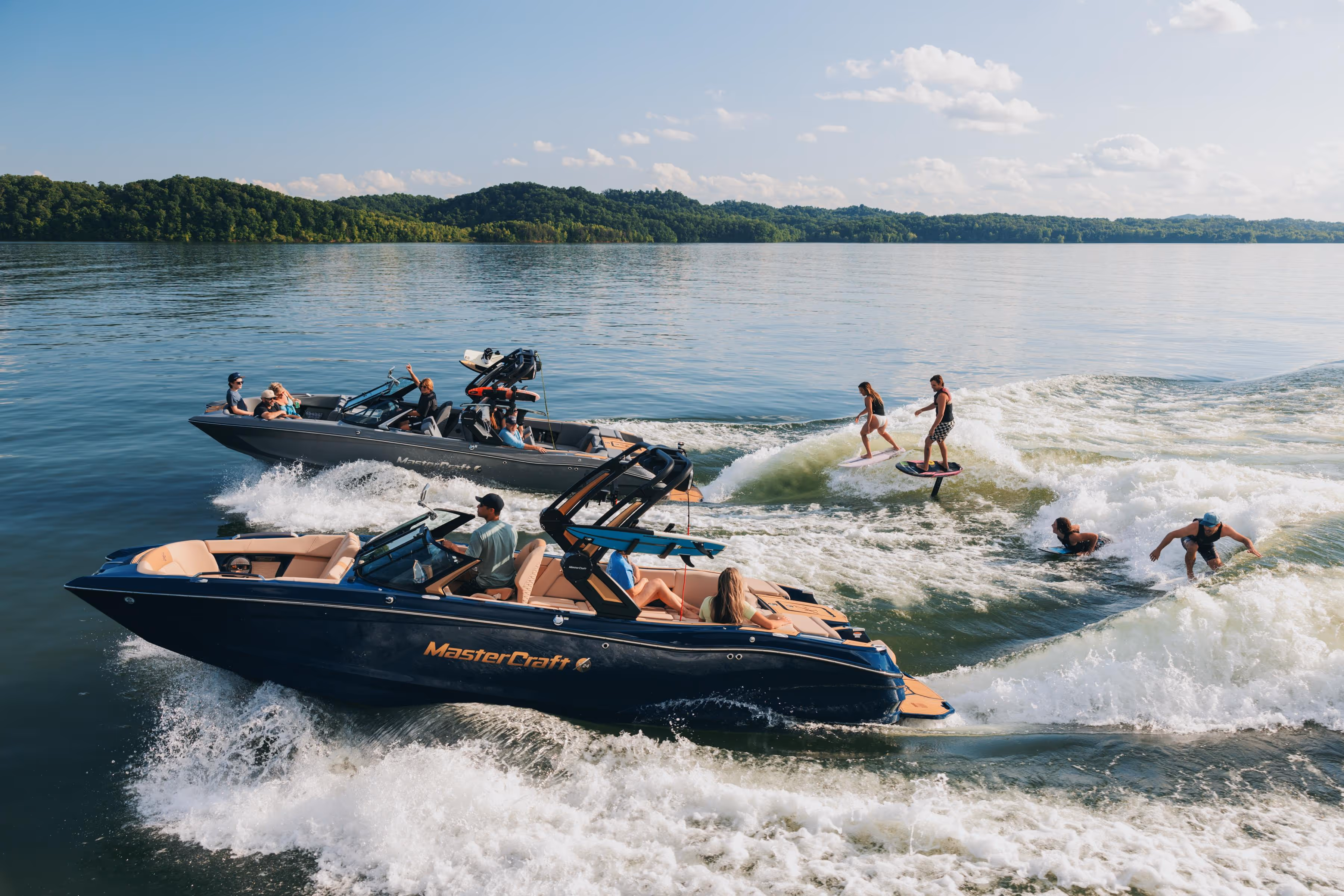 Three people smiling and chatting on a sailboat with calm water and a city skyline in the background.