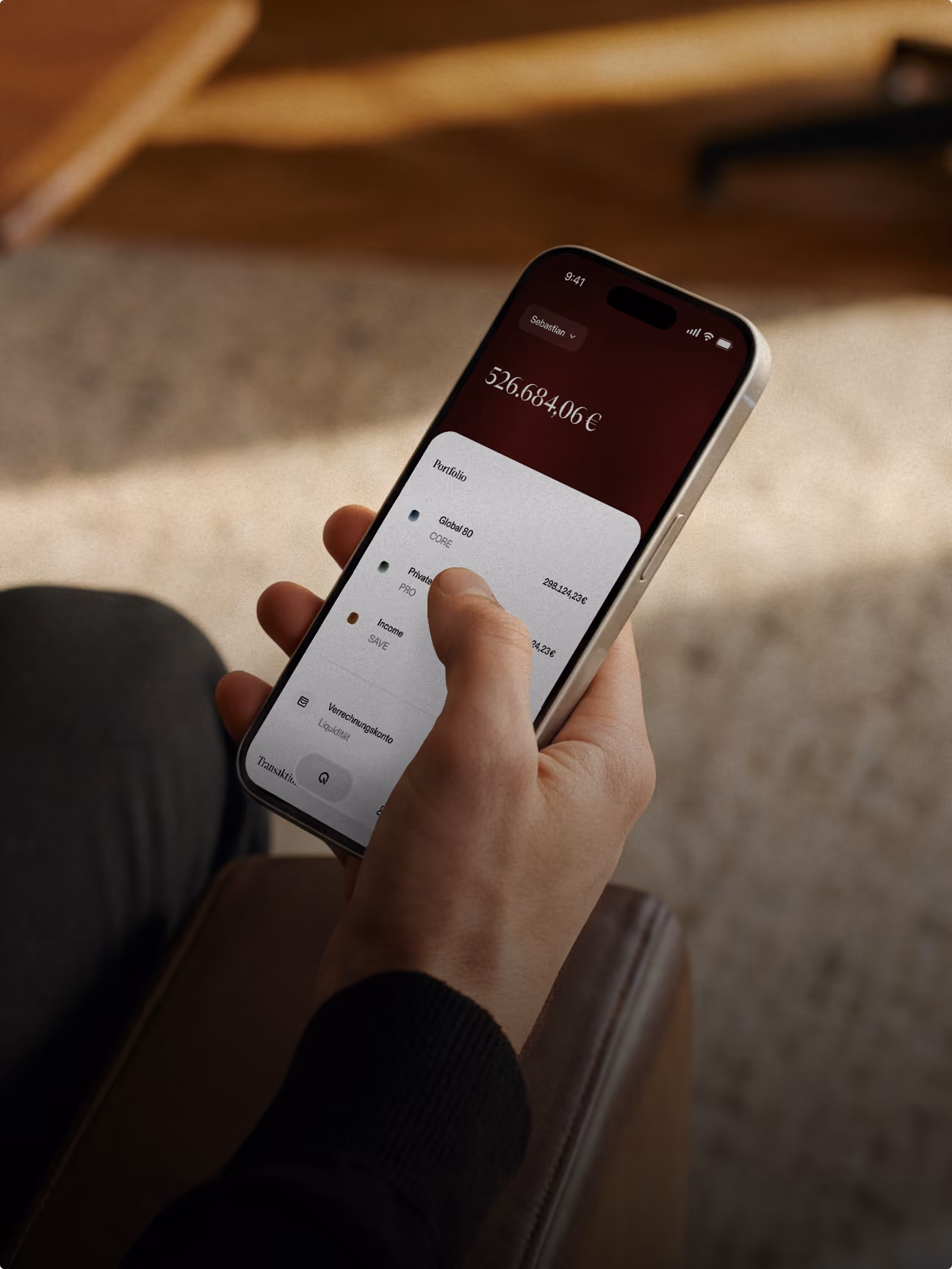 Hand hält Smartphone mit Finanz-App und Kontostand von 526.684,06 Euro