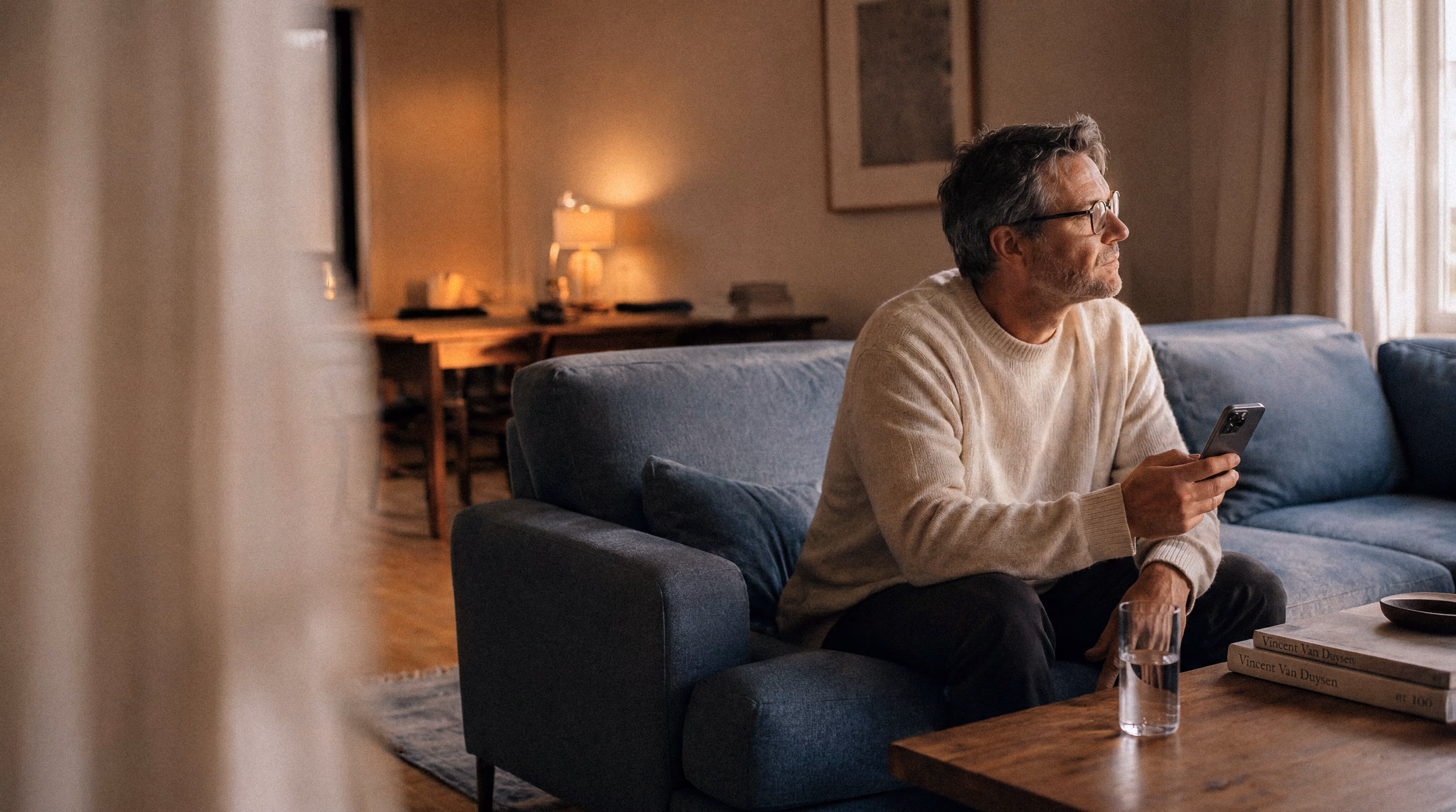 Mann sitzt mit Smartphone auf einem Sofa