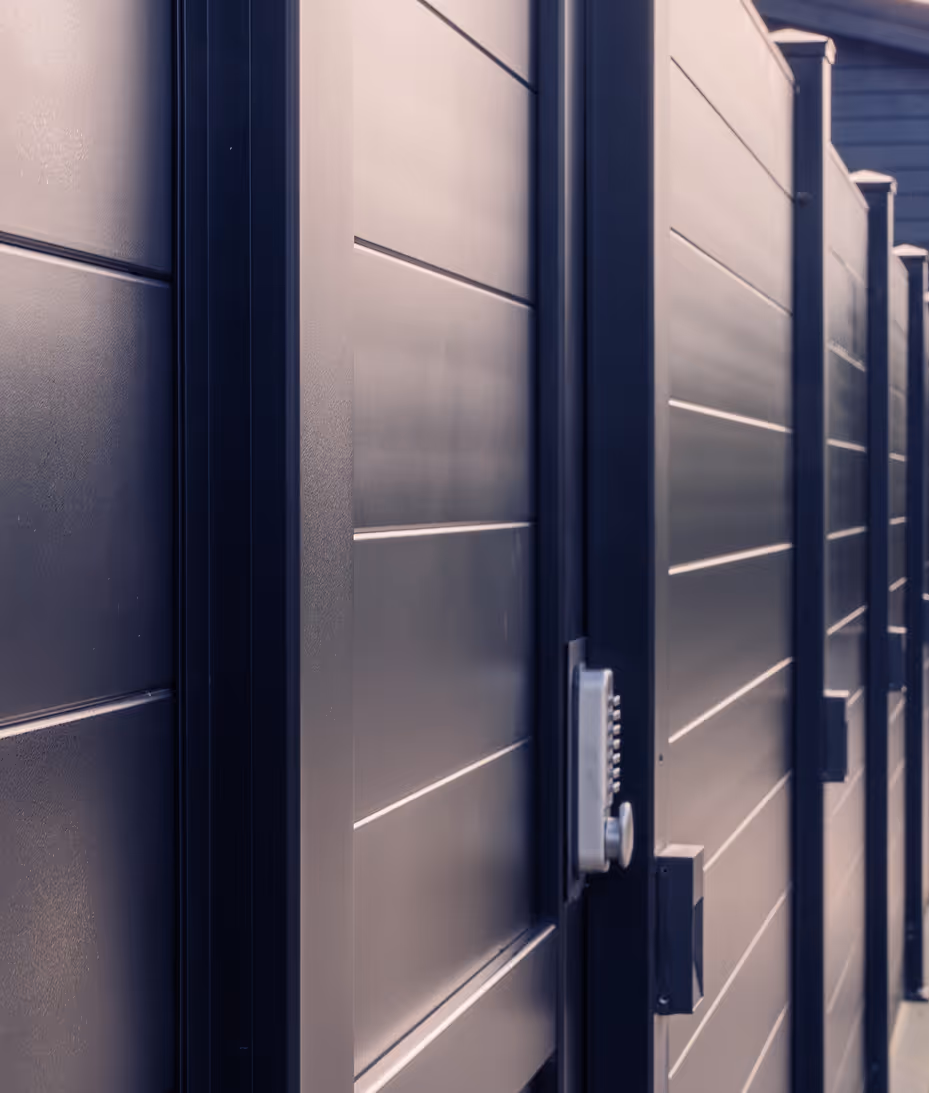 Close-up of a modern black metal fence with horizontal panels and a keypad lock on the gate.