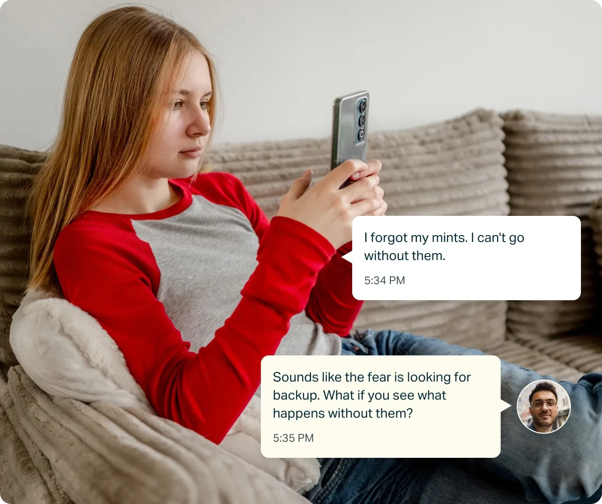 Young woman sitting in a chair looking at her phone with text messages discussing resisting the urge to check due to OCD.