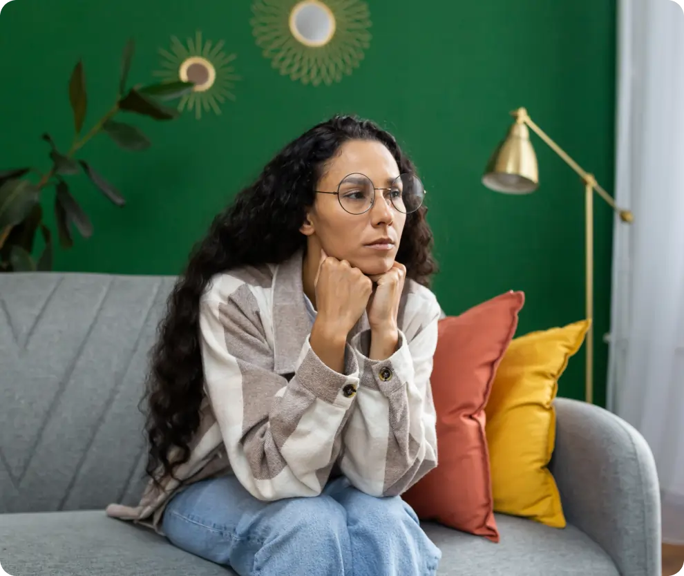 Girl with long brown hair sitting on couch daydreaming