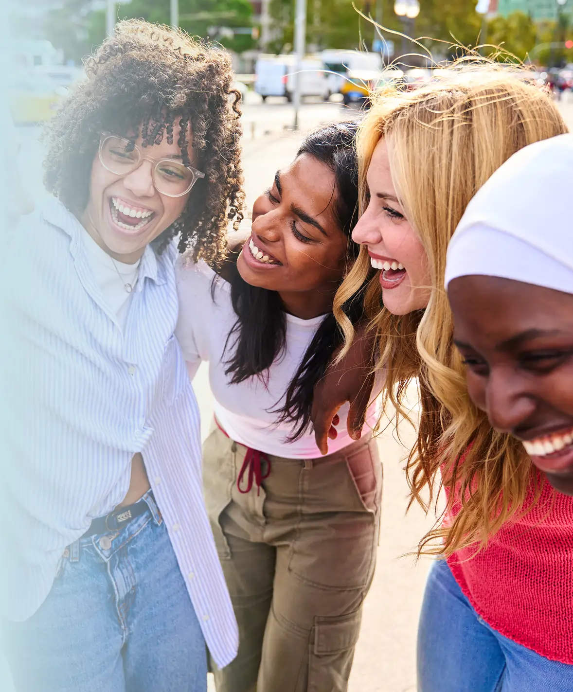 Group of six diverse women smiling and hugging each other outdoors.