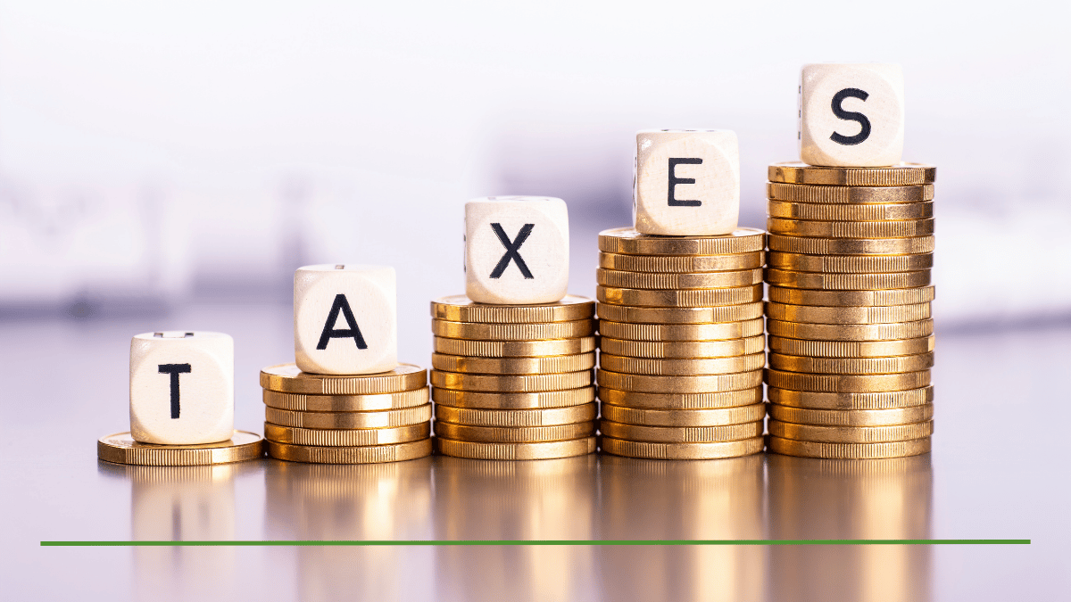 Wooden dice spelling "TAXES" stacked on rising piles of coins, representing retirement tax planning