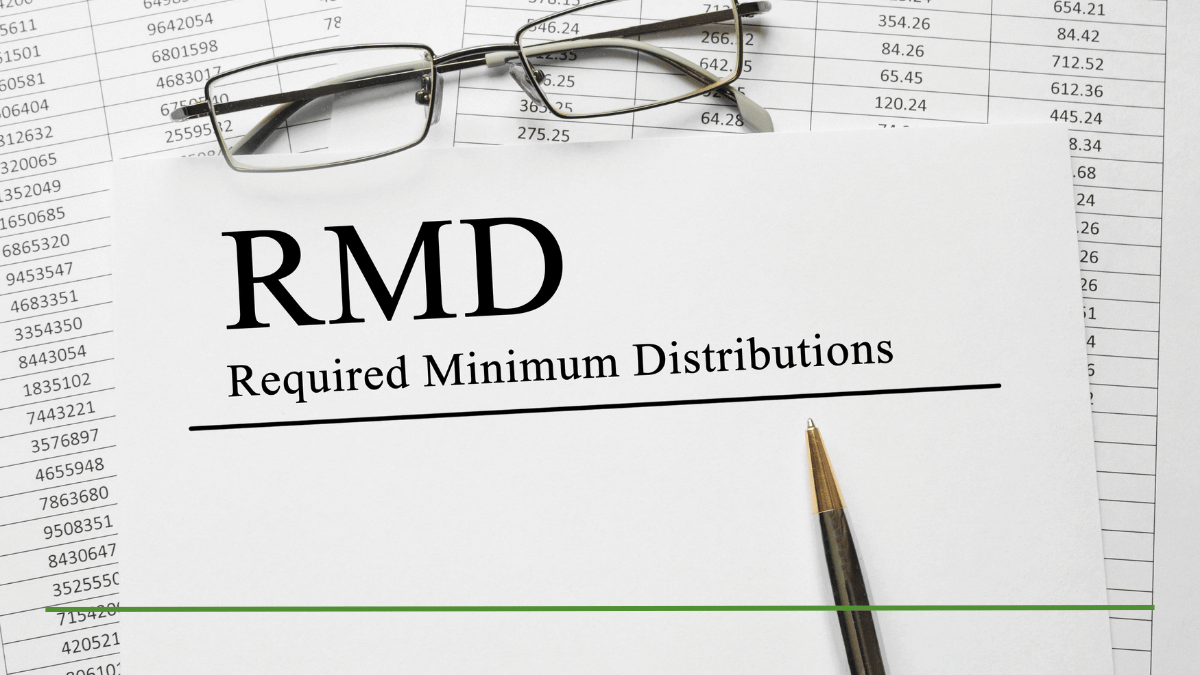 A paper titled 'RMD — Required Minimum Distributions' resting on financial statements, with reading glasses and a pen — representing retirement account withdrawal rules.