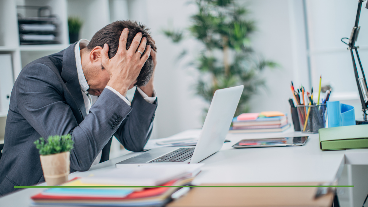 Stressed retiree with head in hands at desk, frustrated by RMD tax impact