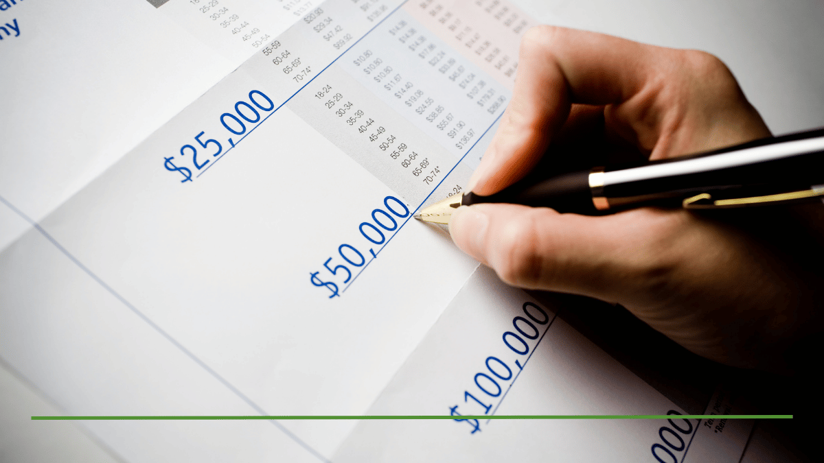Hand signing a document showing $25,000, $50,000, and $100,000 Roth IRA conversion amounts on a tax bracket worksheet