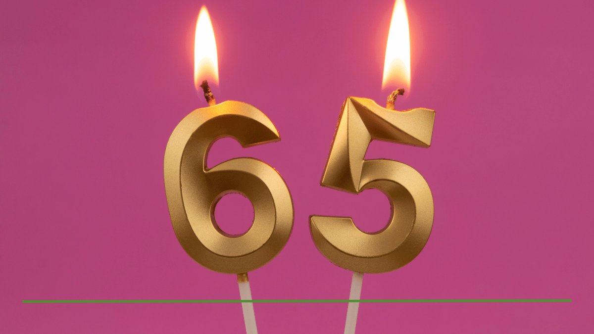 Gold number 65 birthday candles lit against a pink background, symbolizing turning 65 and considering a Roth conversion