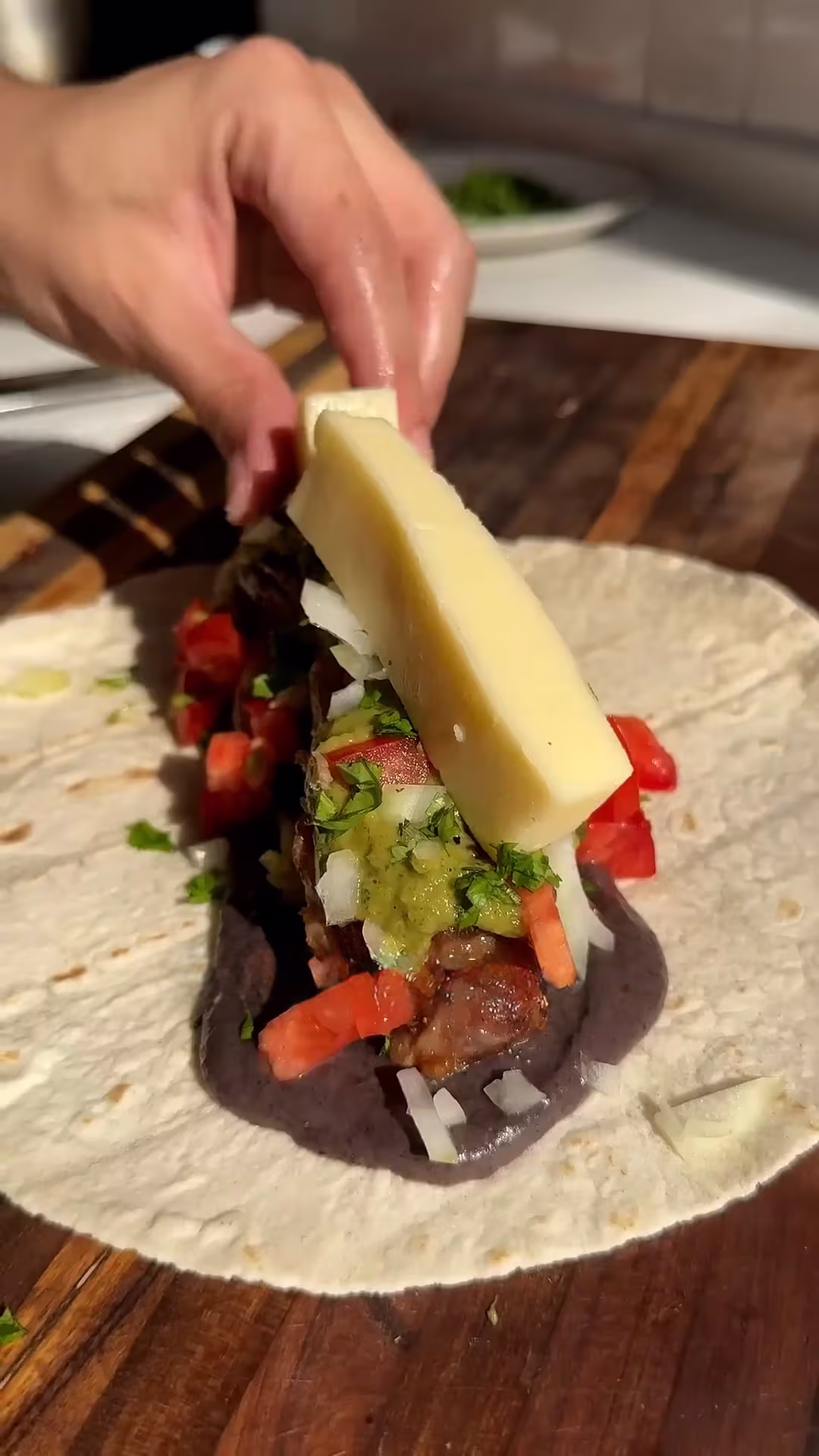armar el burrito con una tortilla, salsa de frijoles, relleno, salsa verde, y queso.
