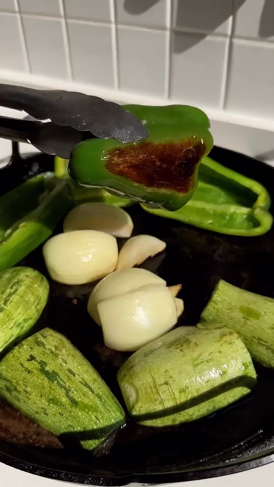 tatemar los morrones verdes, la cebolla y el zucchini para hacer la salsa verde casera para burritos