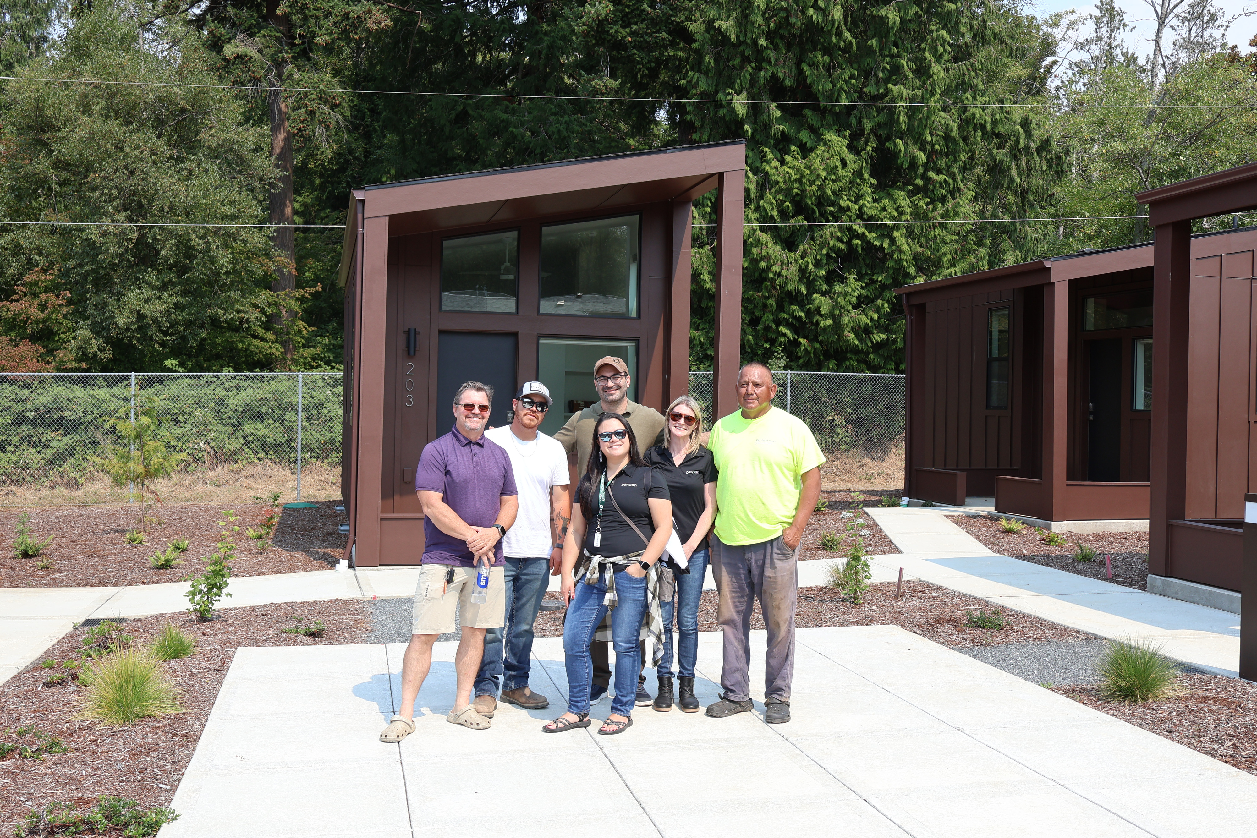 Members of the Dawson Construction crew standing together in front of finished tiny home unit 203 at Crowberry Mini Homes