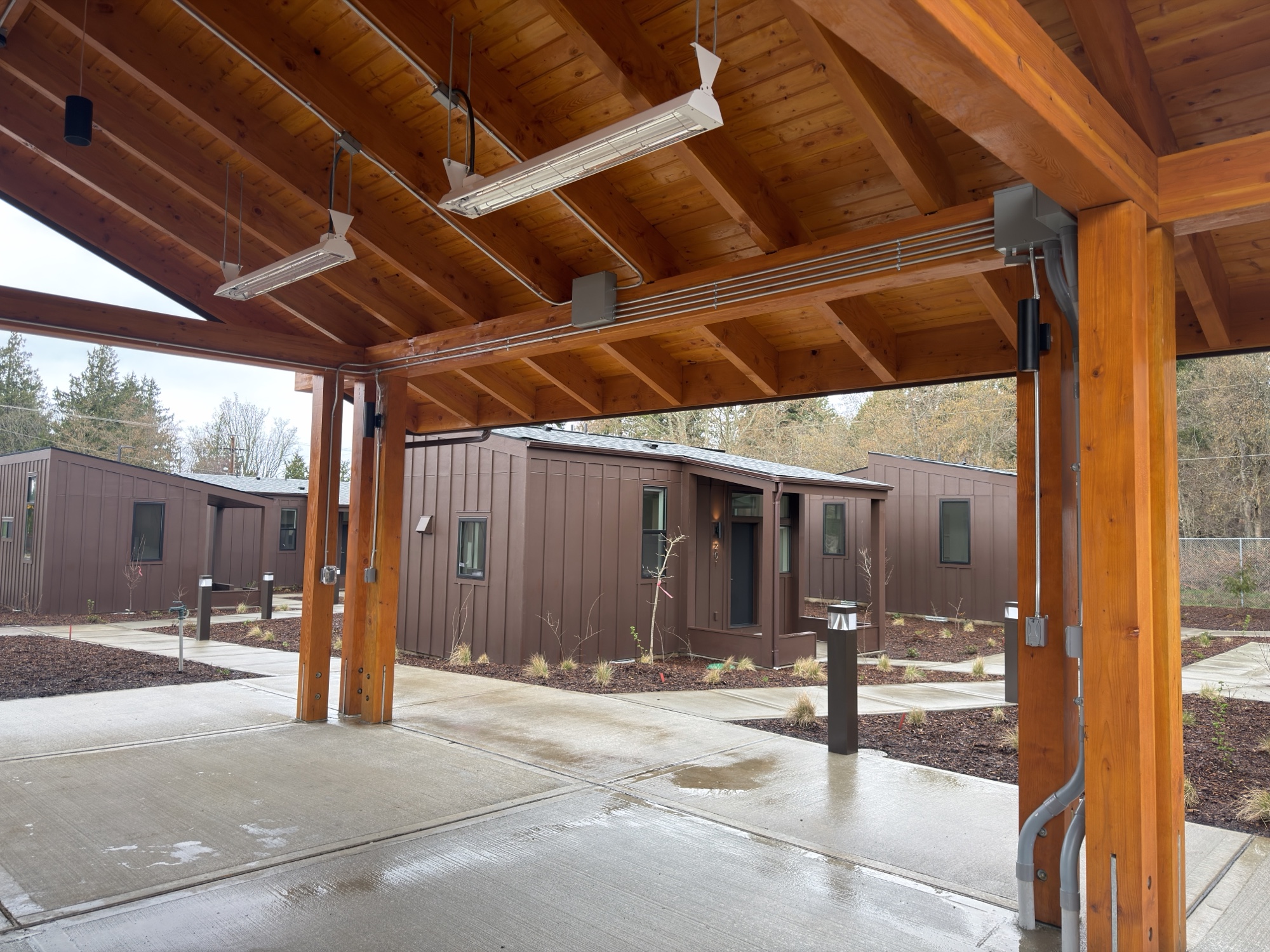 Ground-level view through the covered wood-beam breezeway between Eagle Haven tiny homes