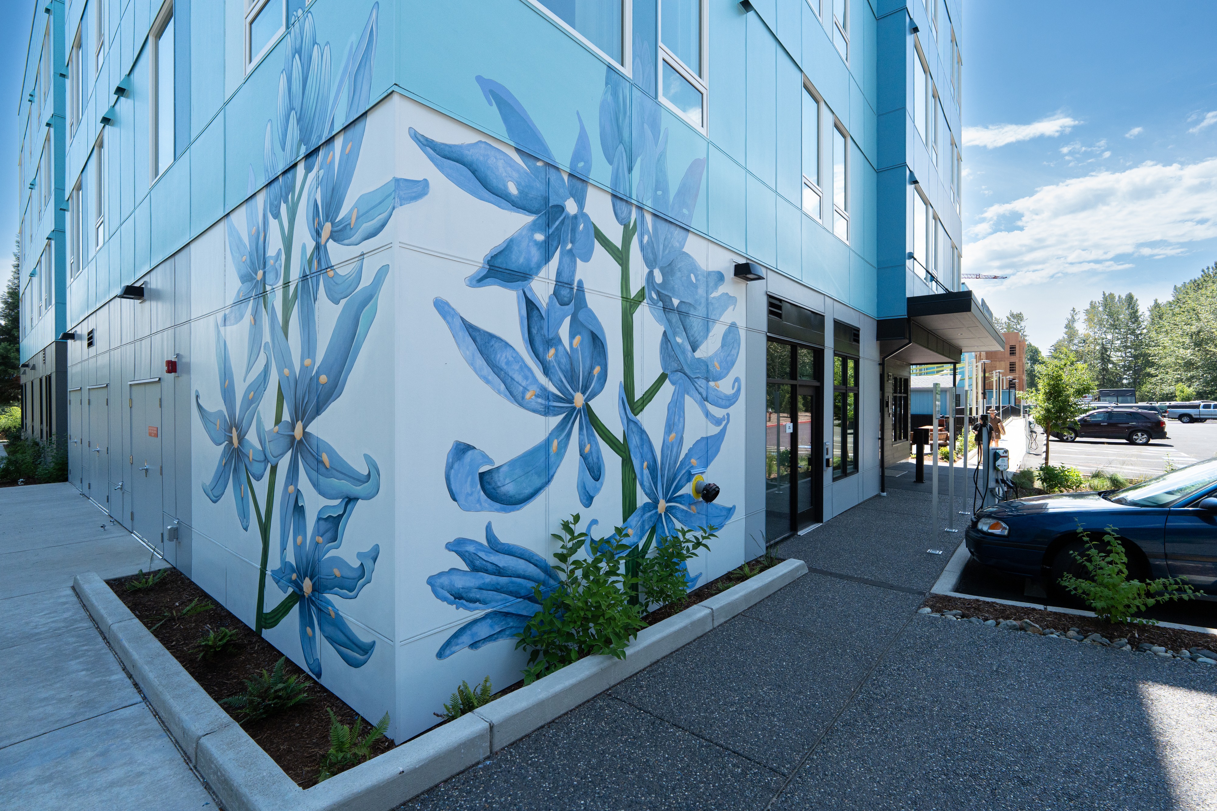 Blue camas flower mural wrapping the building corner at Bellis Fair Family Housing