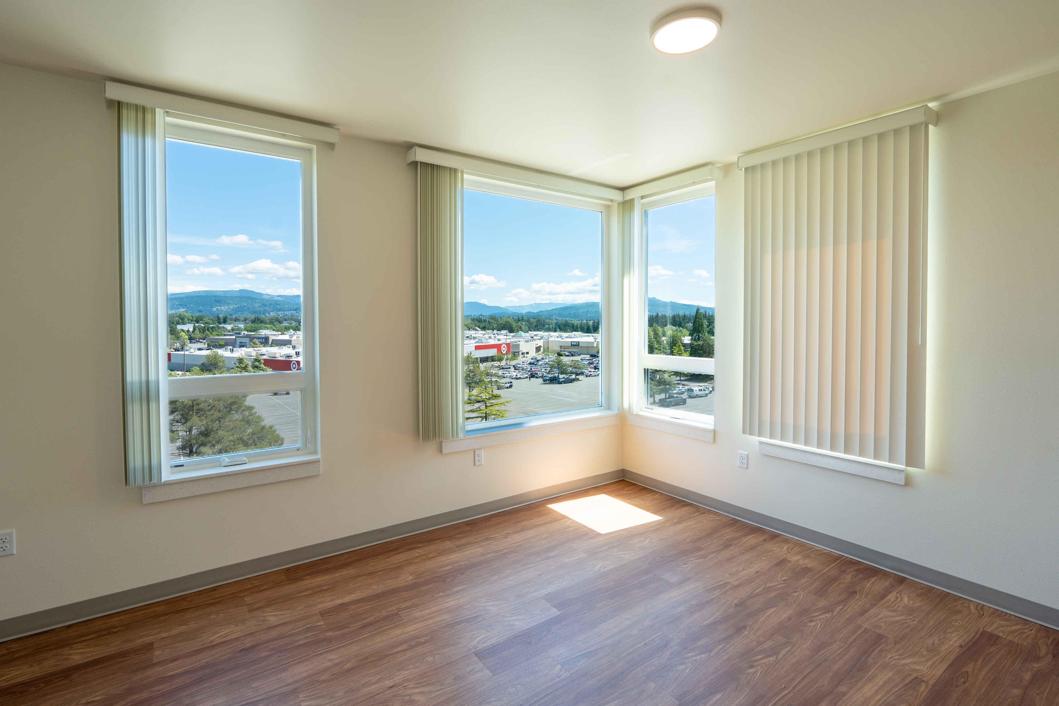 Apartment living room with corner windows and mountain views at Bellis Fair Family Housing