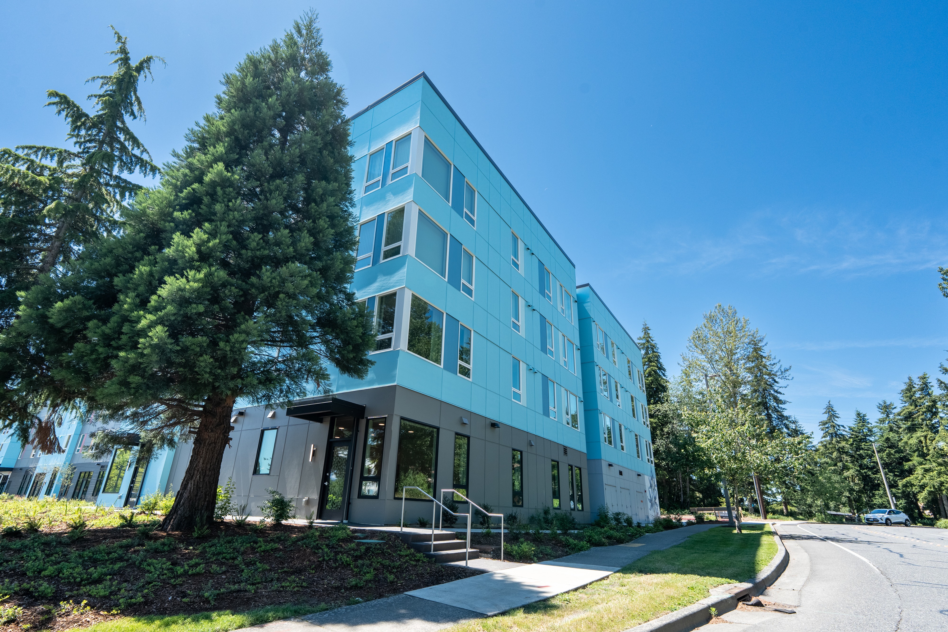 Completed Bellis Fair Family Housing building beside a mature evergreen in Bellingham, Washington