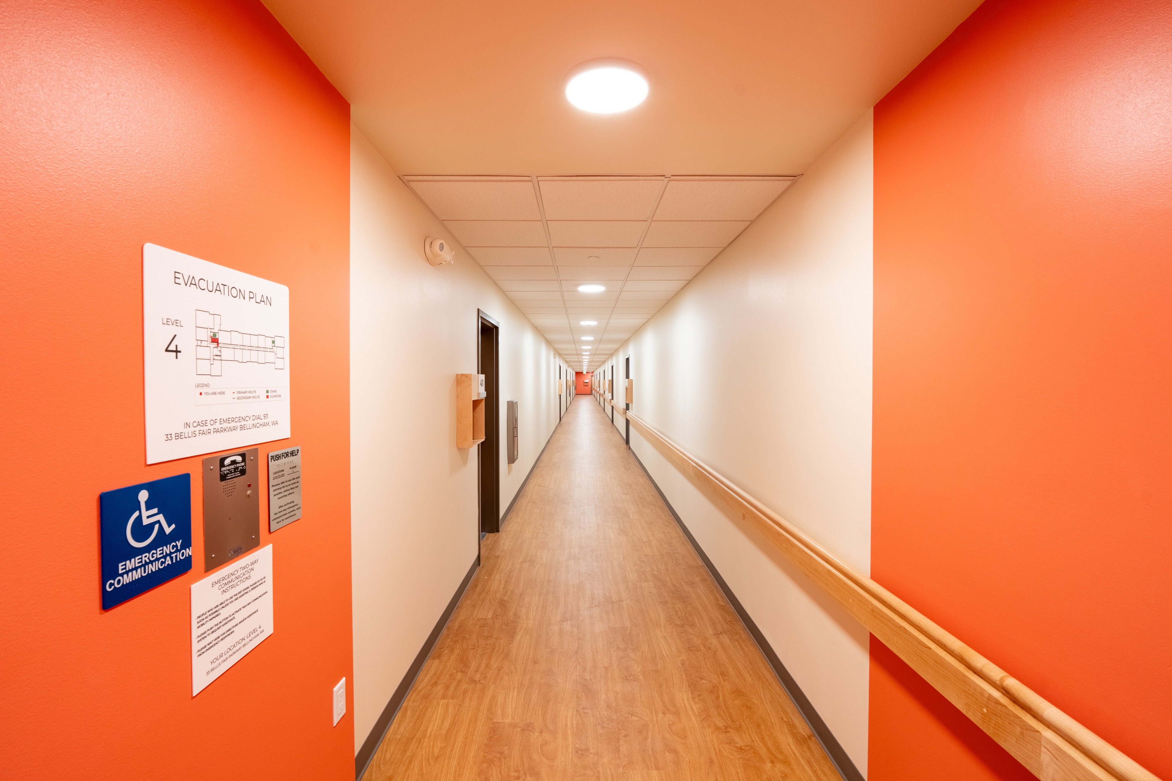 Residential hallway with orange accent walls at Bellis Fair Family Housing