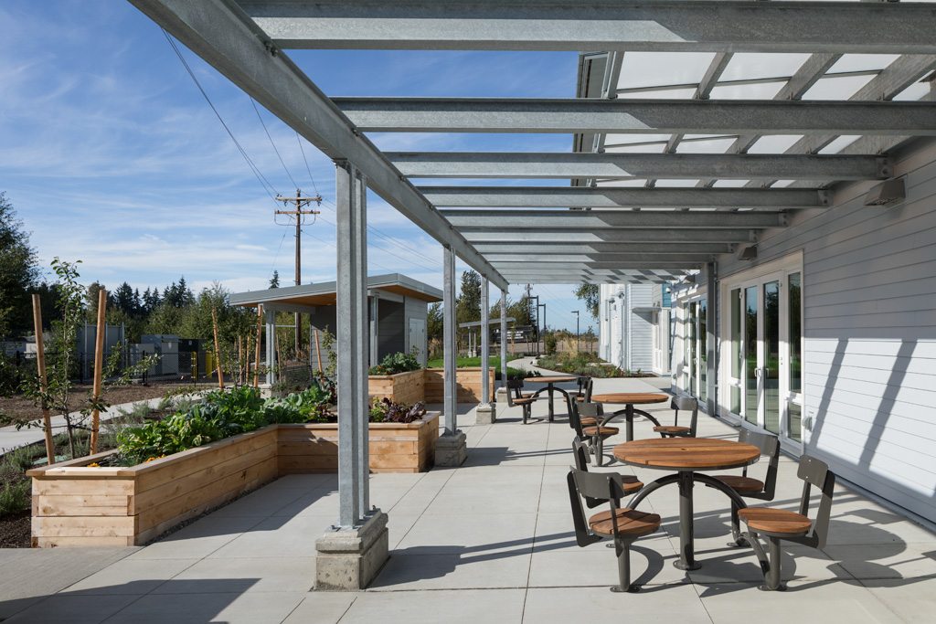 Resident courtyard with steel pergola, raised garden beds and outdoor seating at Clare's Place supportive housing, Everett