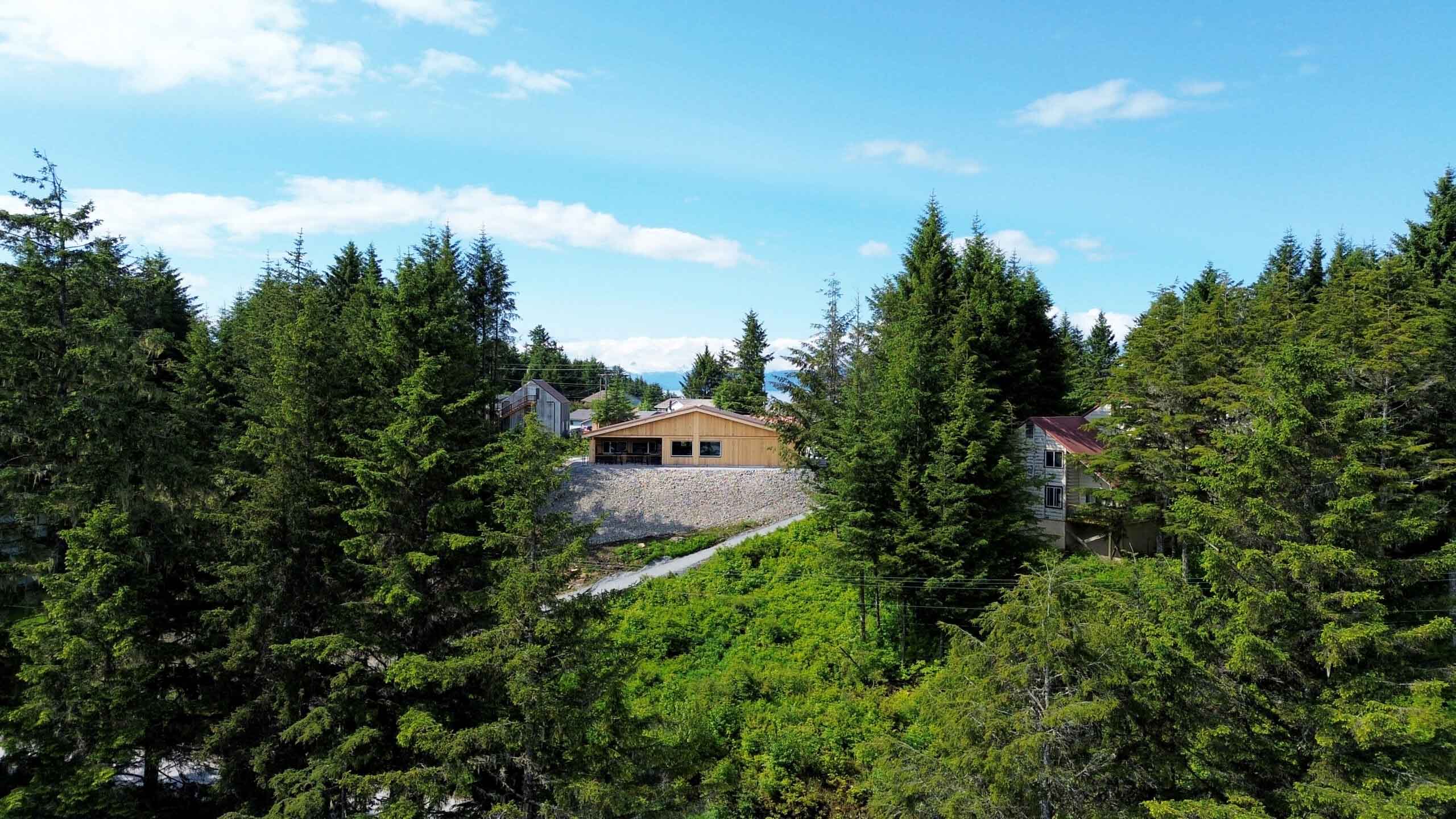 Aerial view of the Angoon Visitor Center on its forested hillside above the water