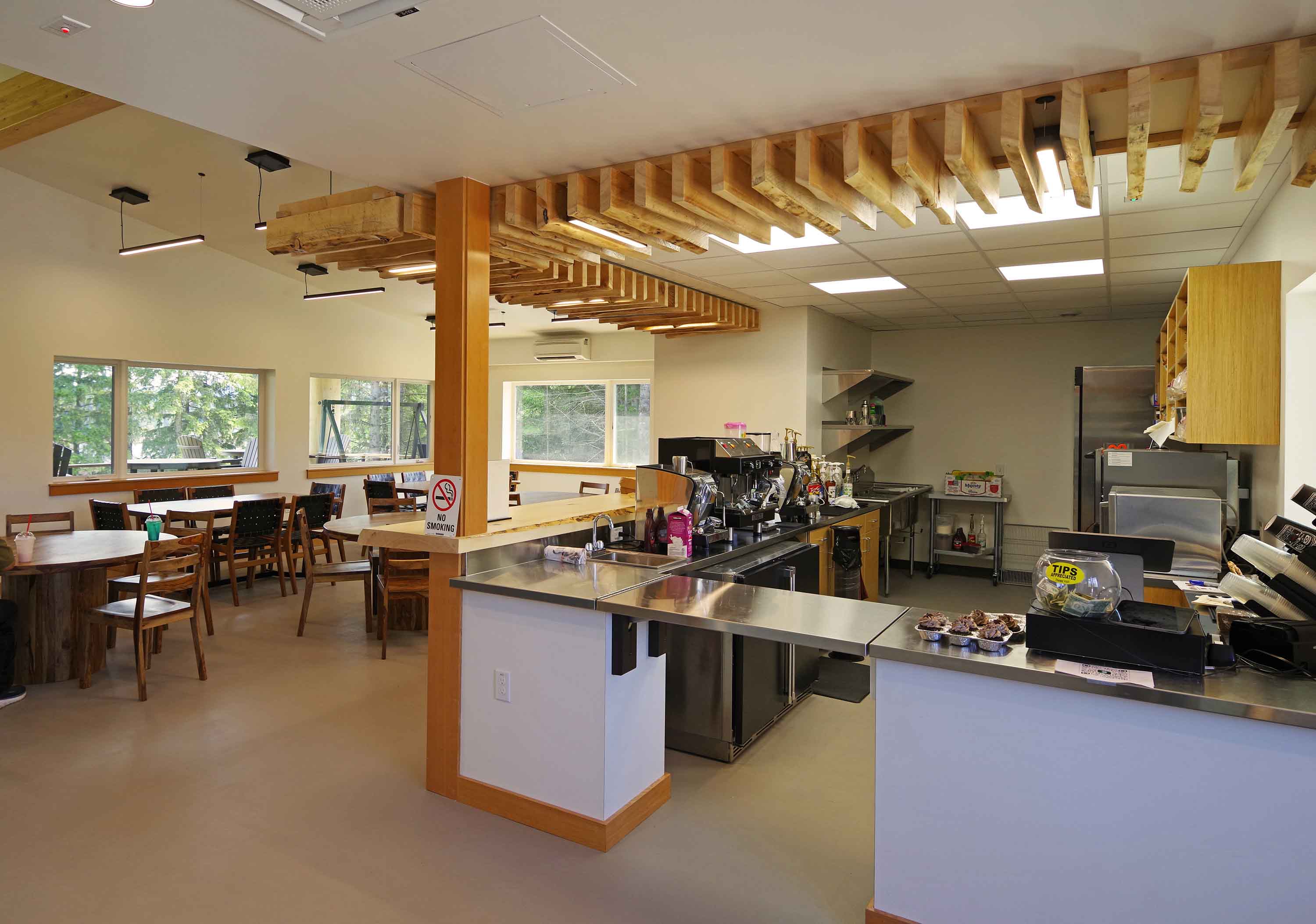 Espresso bar and cafe seating beneath a live-edge timber ceiling at the Angoon Visitor Center