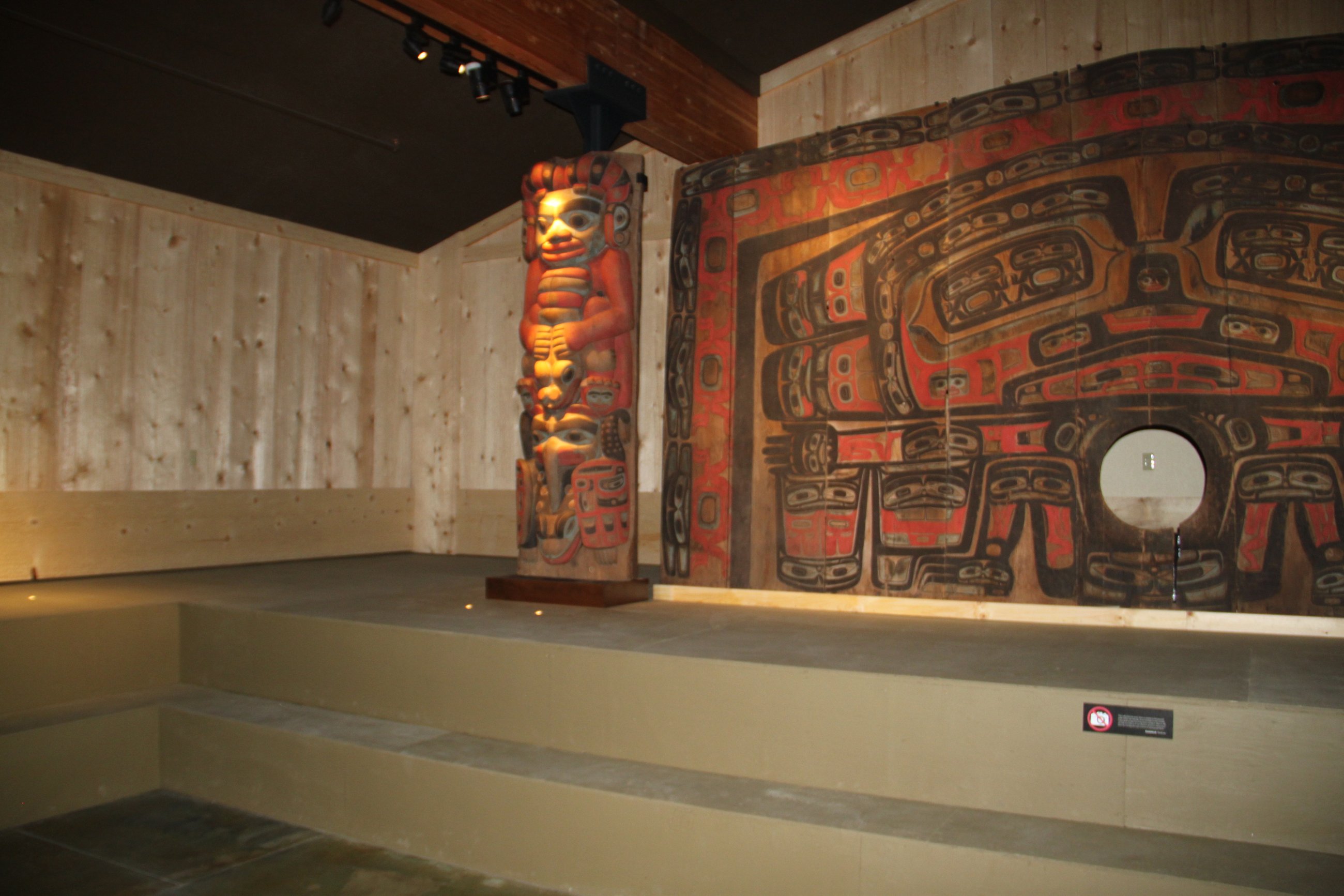 Carved totems and painted screen in the exhibit hall at the Jilkaat Kwaan Cultural Heritage Center