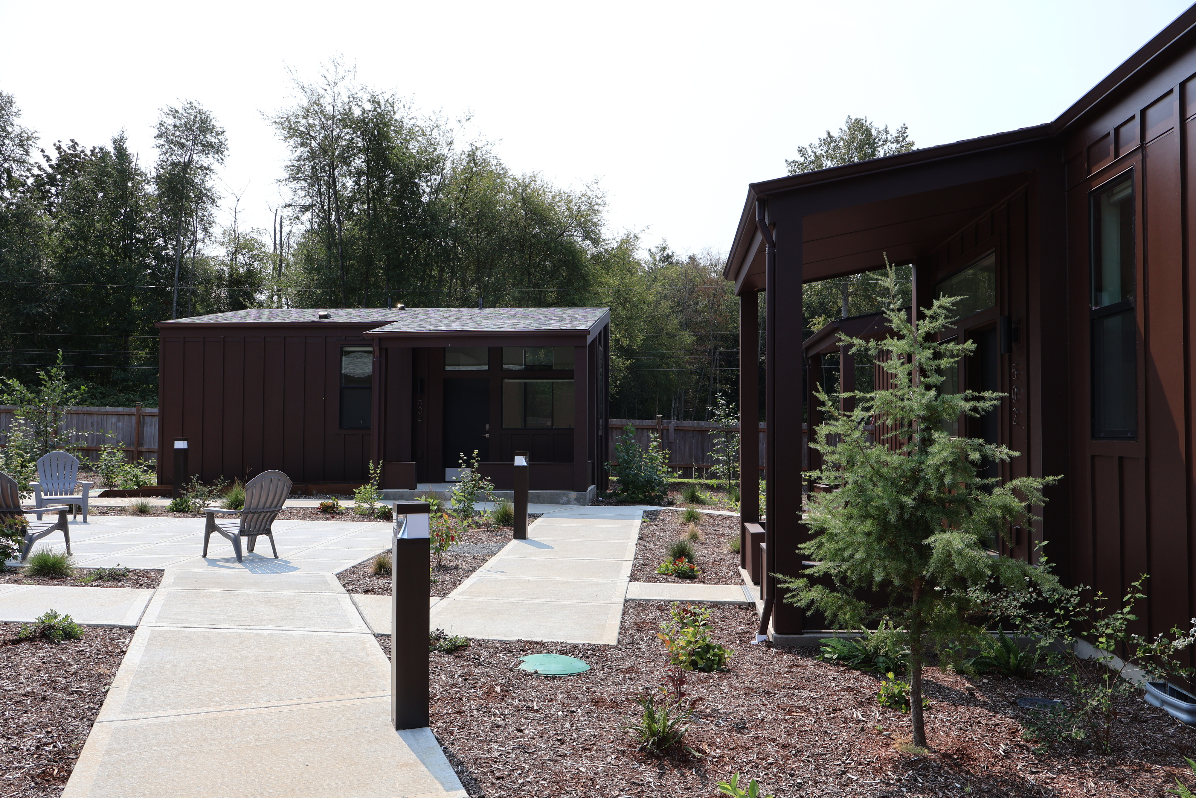 A finished tiny home at Crowberry Mini Homes with board and batten siding, a shed roof, a concrete walkway, and new landscaping