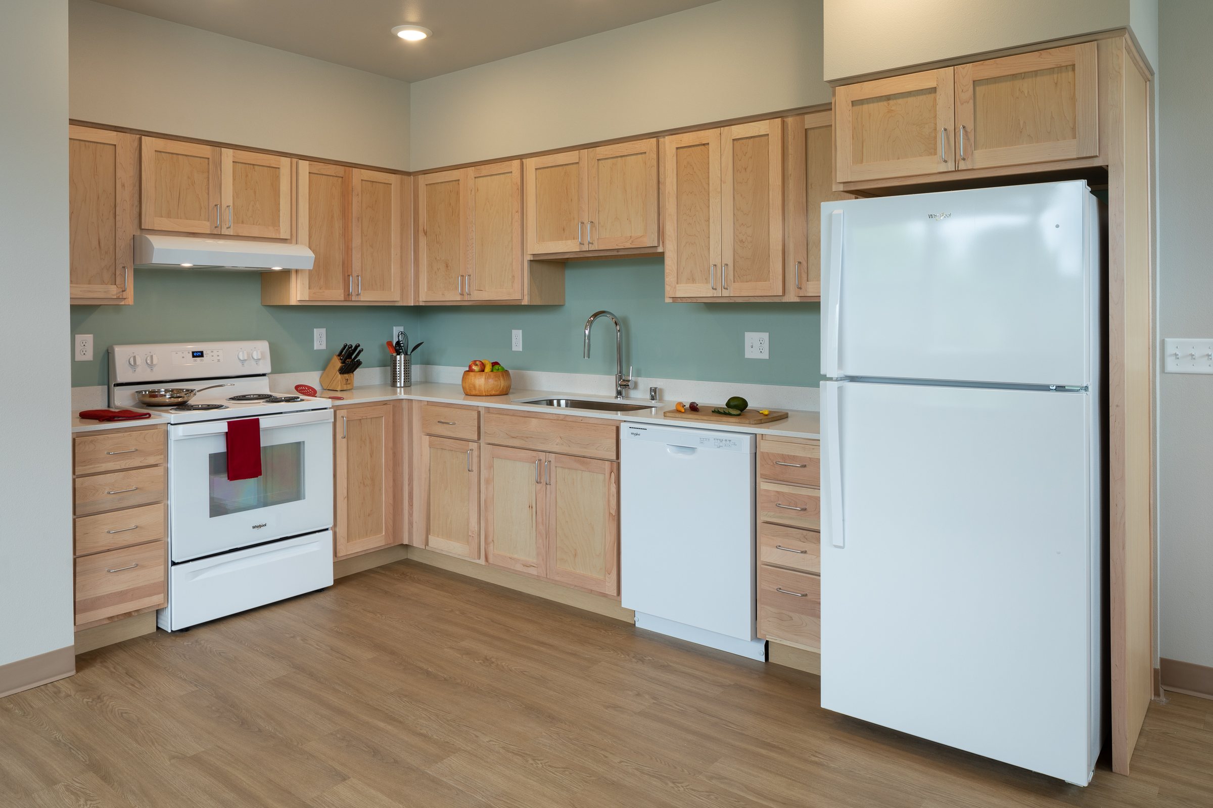 Apartment kitchen with maple cabinets and white appliances at Ballington Flats