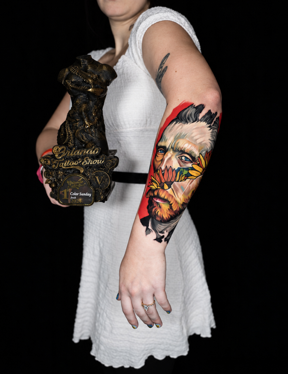 Client holding a tattoo show trophy and showing a color Van Gogh forearm tattoo by Jesus