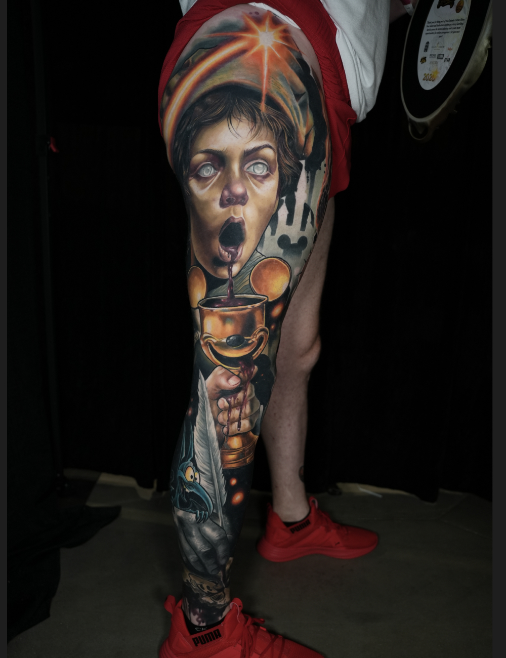 Color surrealism leg sleeve tattoo of a wide-eyed child's face with a golden chalice by LuisK Osorio