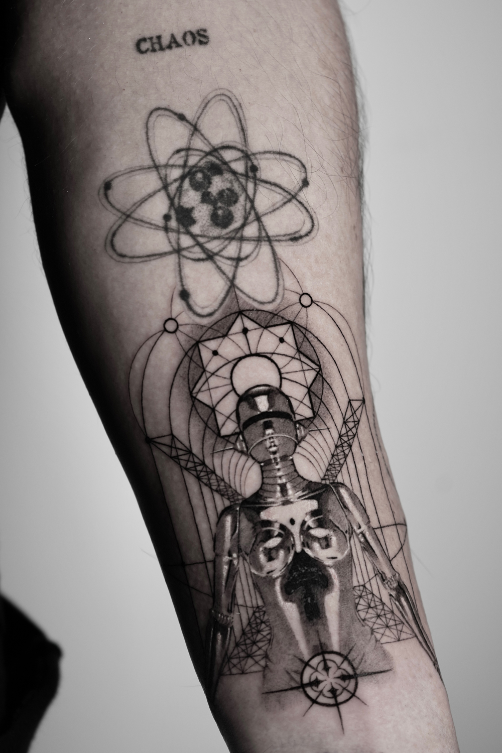 Geometric tattoo of an atom, mandala and skeletal figure with fine linework on the forearm at The Secret Tattoo Studio in Tampa