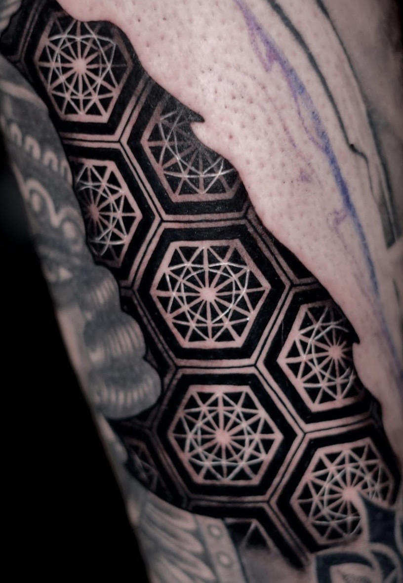 Geometric tattoo of hexagons filled with sacred geometry stars on the arm at The Secret Tattoo Studio in Tampa