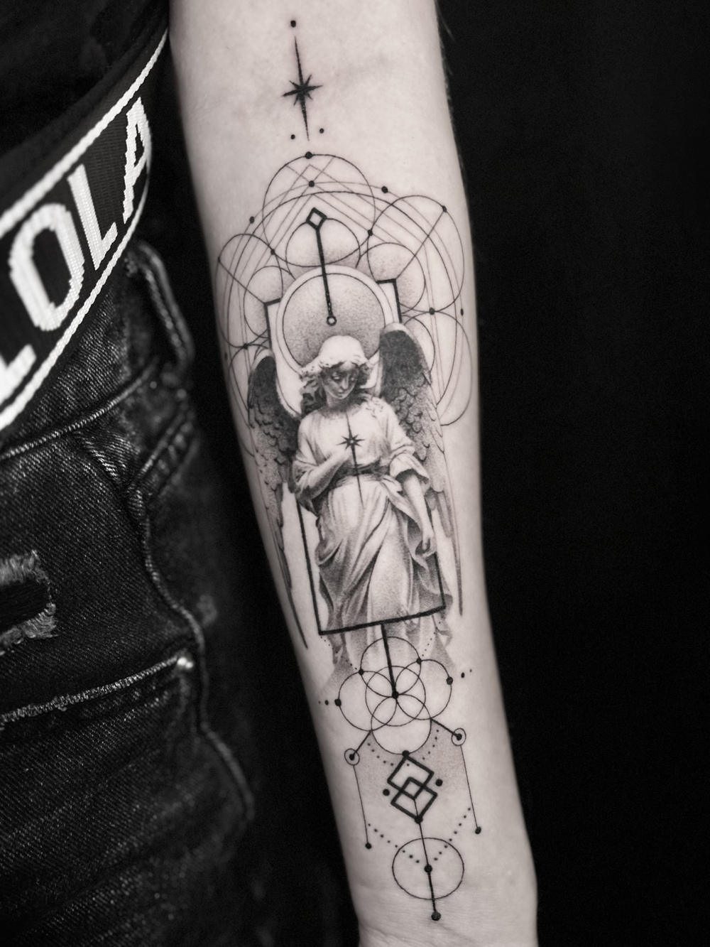 Geometric tattoo of a praying angel statue framed by sacred geometry circles on the forearm at The Secret Tattoo Studio in Tampa