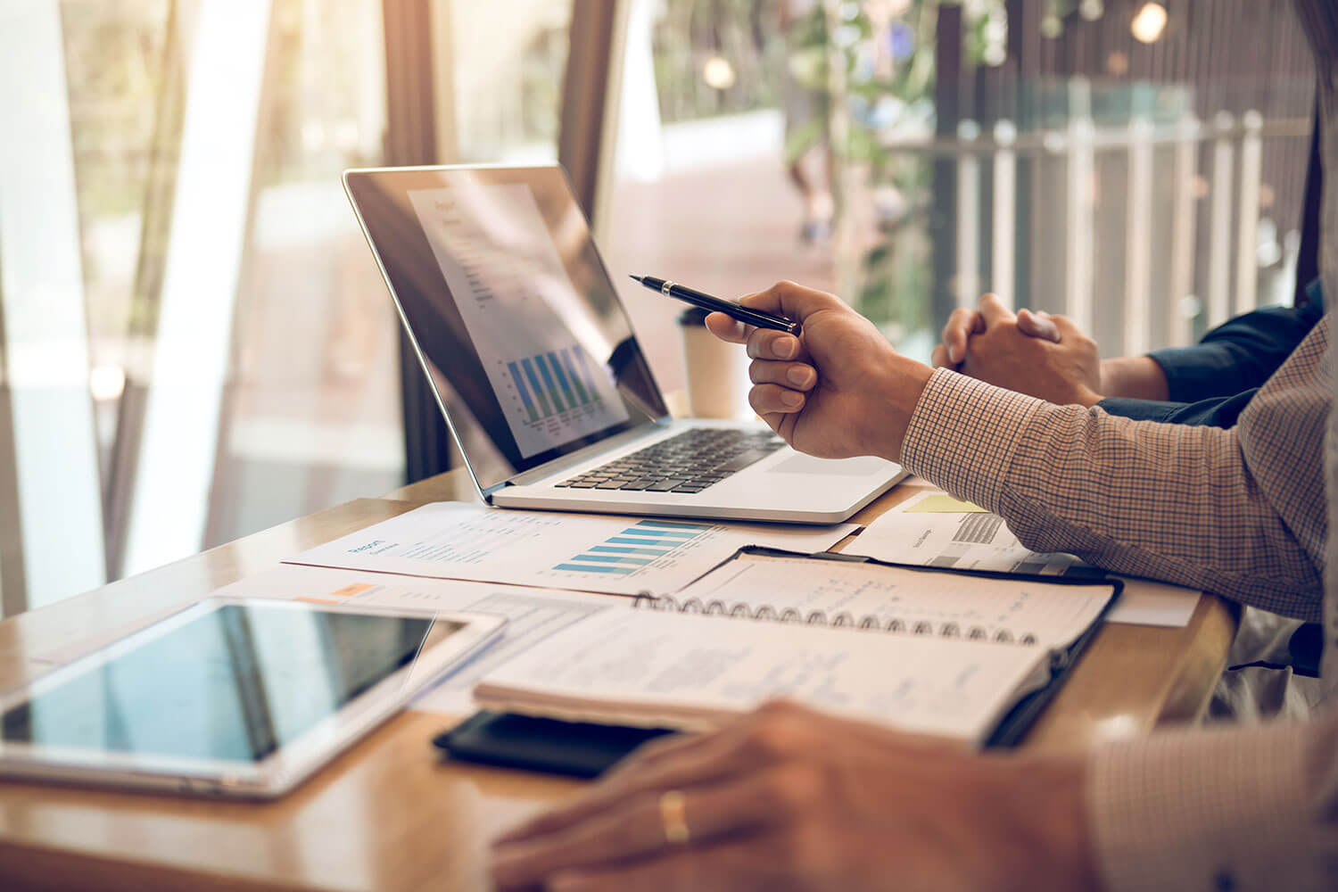 Business professionals analyzing data and research reports in front of a laptop