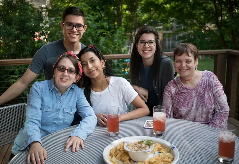 A person with a disability with a group of smiling people at a picnic table