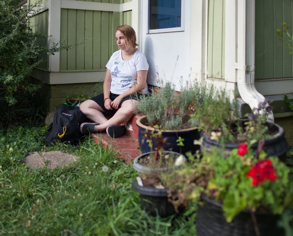 A young person sitting alone with their backpack