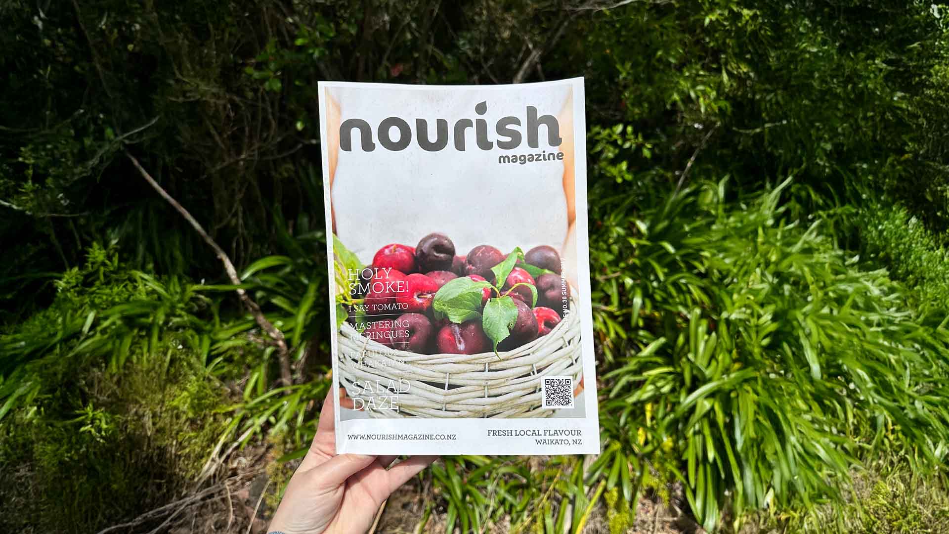 Nourish magazine held outdoors showing fresh fruit basket cover image, saddle stitch binding printed by Mainprint