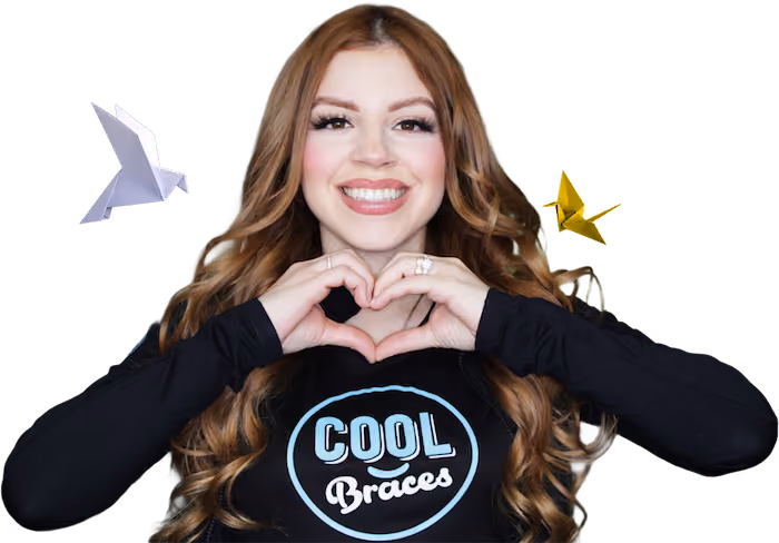 Woman smiling, wearing a Cool Braces shirt, and making the shape of a heart with her hands