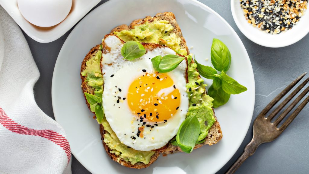 Spread avocado on toast and top it with poached eggs