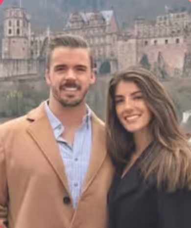 Smiling man and woman standing close together outdoors with a historic castle in the background.