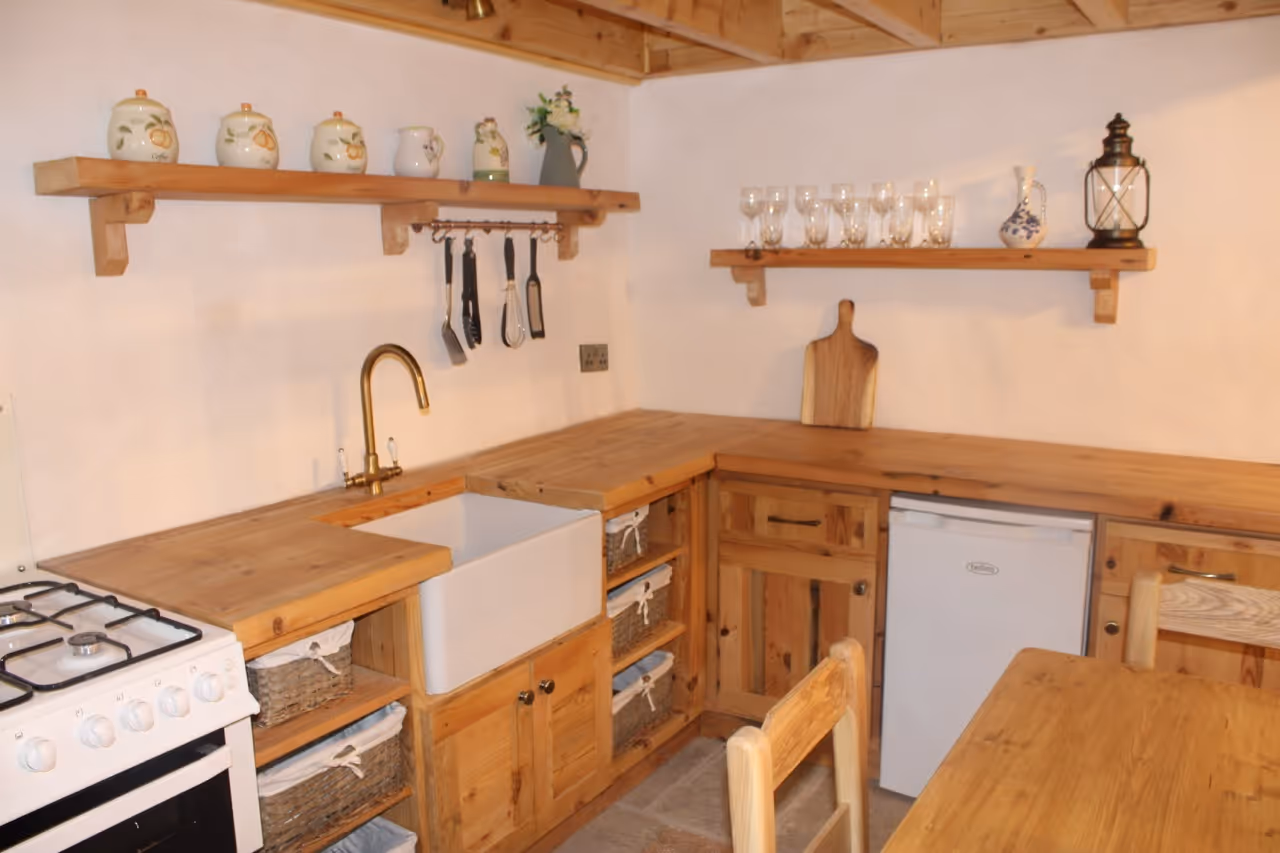Cozy wooden kitchen with open shelves, farmhouse sink, and wicker baskets under the counter.