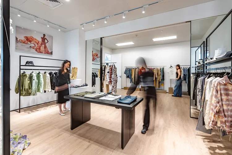 Chelsey House showroom interior with racks of clothes, a central display table, and three people browsing apparel.