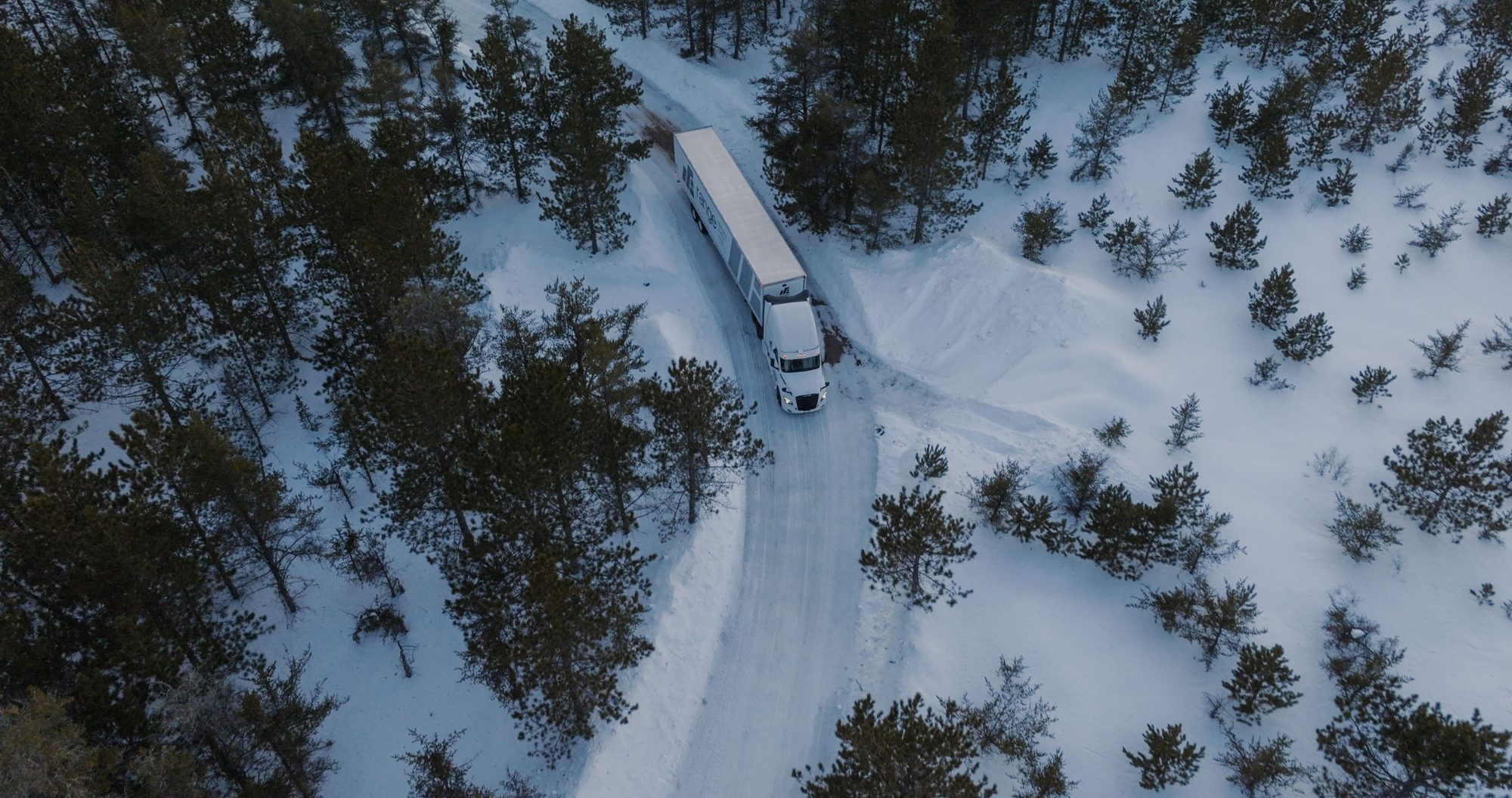 Aerial view of a Range eTrailer semi-truck on a snow-covered forest road during winter testing