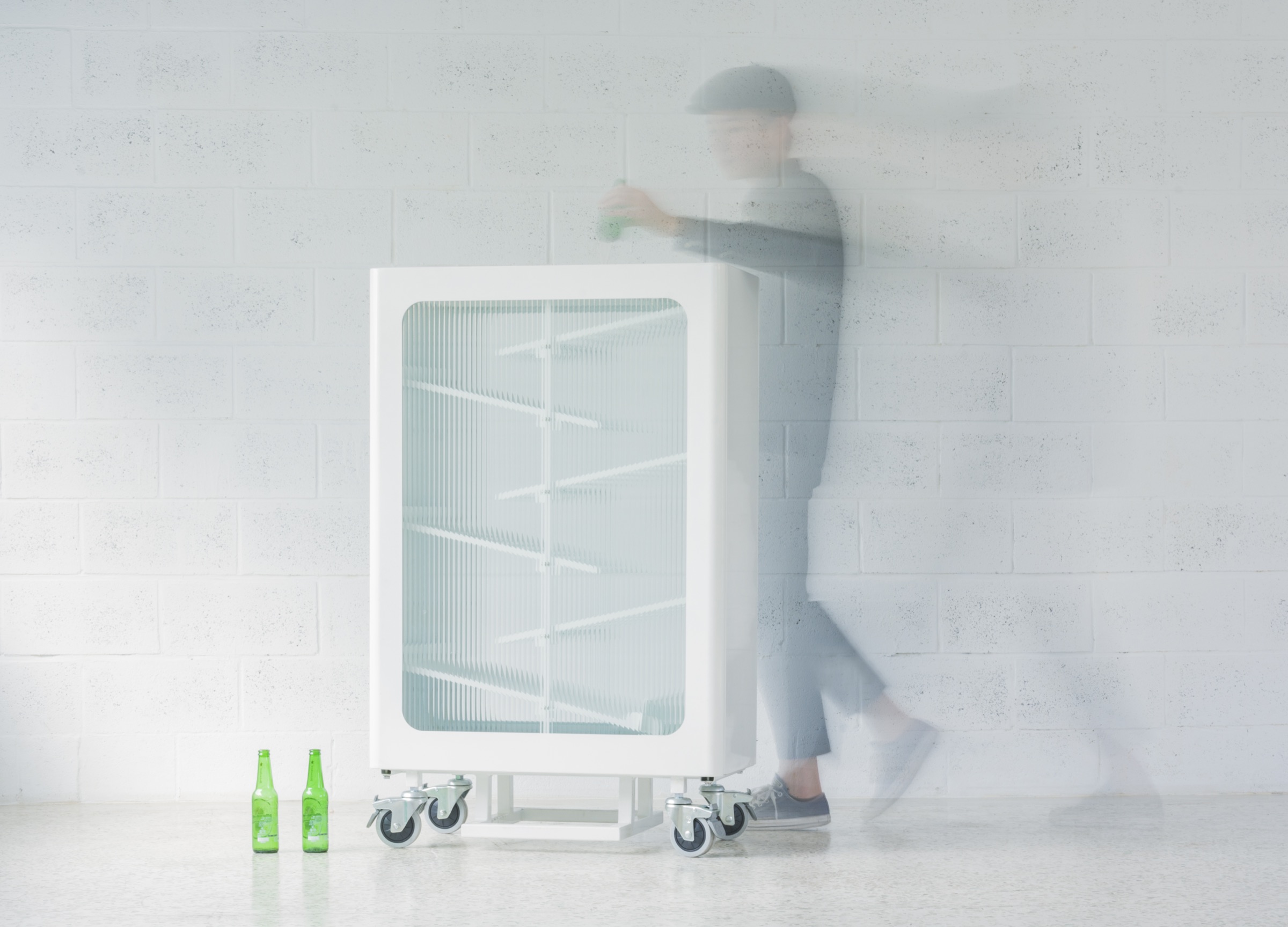 The Interactive Glass Recycling Bin in a white interior as a passer-by walks past